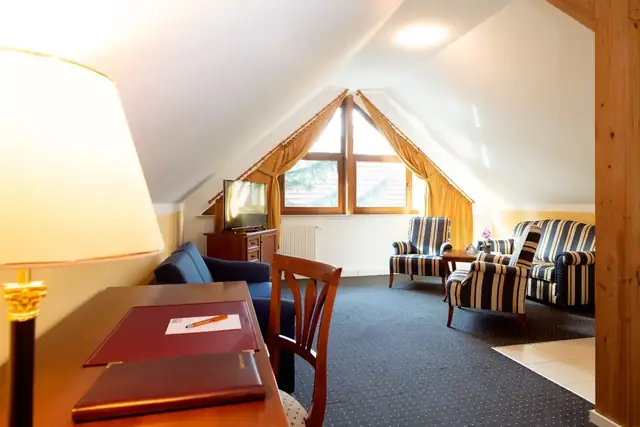 Living area of the attic suite with desk, armchairs and gable window – Hotel am Katharinenholz Potsdam