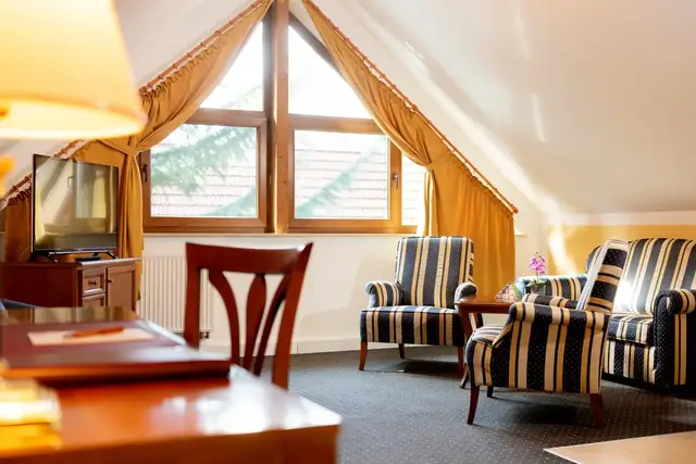 Seating area with armchairs and flat-screen TV in the living room of the attic suite – Hotel am Katharinenholz Potsdam