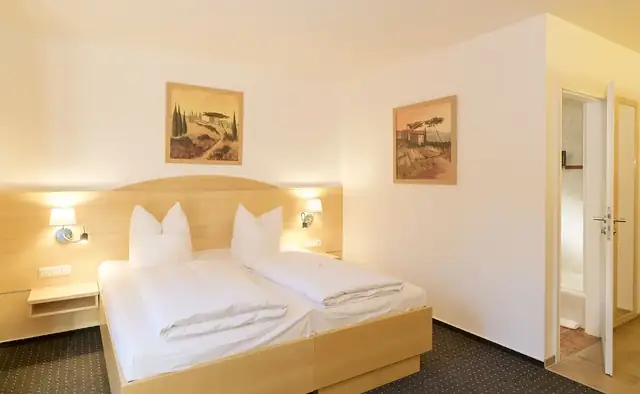 Doppelzimmer im Erdgeschoss mit Doppelbett, Sesseln und Terrassentür zum Garten – Hotel Potsdam am Katharinenholz