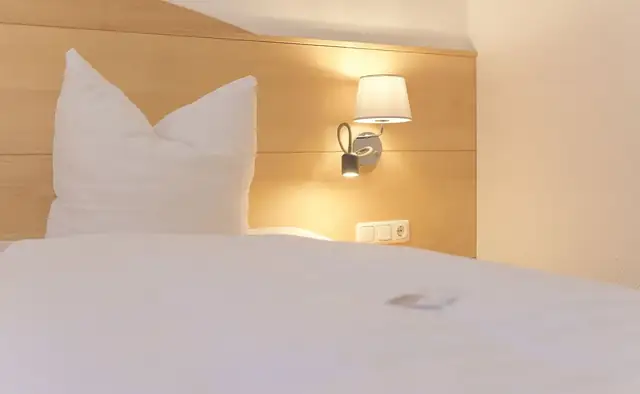 Detail des frisch bezogenen Betts mit Leseleuchte im Doppelzimmer – Hotel Potsdam am Katharinenholz