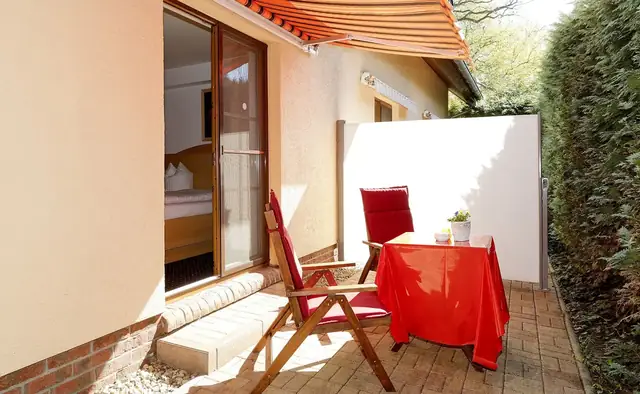Eigene Terrasse mit Markise, Tisch und Stühlen am Hotelgarten – Hotel Potsdam am Katharinenholz