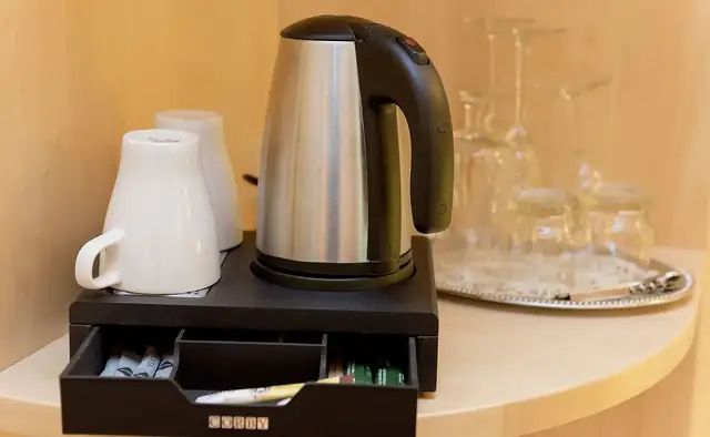 Kaffee- und Tee-Station mit Wasserkocher, Tassen und Gläsern im Zimmer – Hotel Potsdam am Katharinenholz