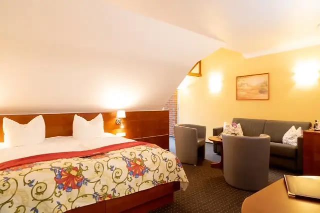 Double bed and upholstered suite with sofa in the Superior room – Hotel Potsdam am Katharinenholz