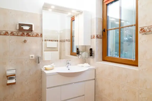Vanity with mirror and window in the bathroom of the Superior room – Hotel Potsdam am Katharinenholz